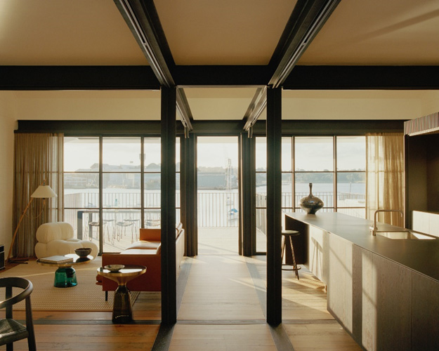 A minimalist open living space with windows facing out to a harbour.
