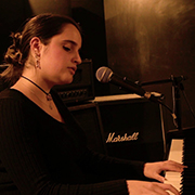 a girl plays the piano wearing a black top