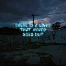Blue neon sign in cursive writing against a stormy sky reads 'There is a light that never goes out'