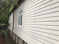 Exterior wall expanse in creme slatted weatherboard white window frames with some natural framing