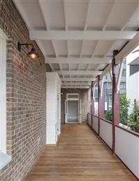 Covered verandah space with timber flooring brick wall red and creme featured balustrades and door frames