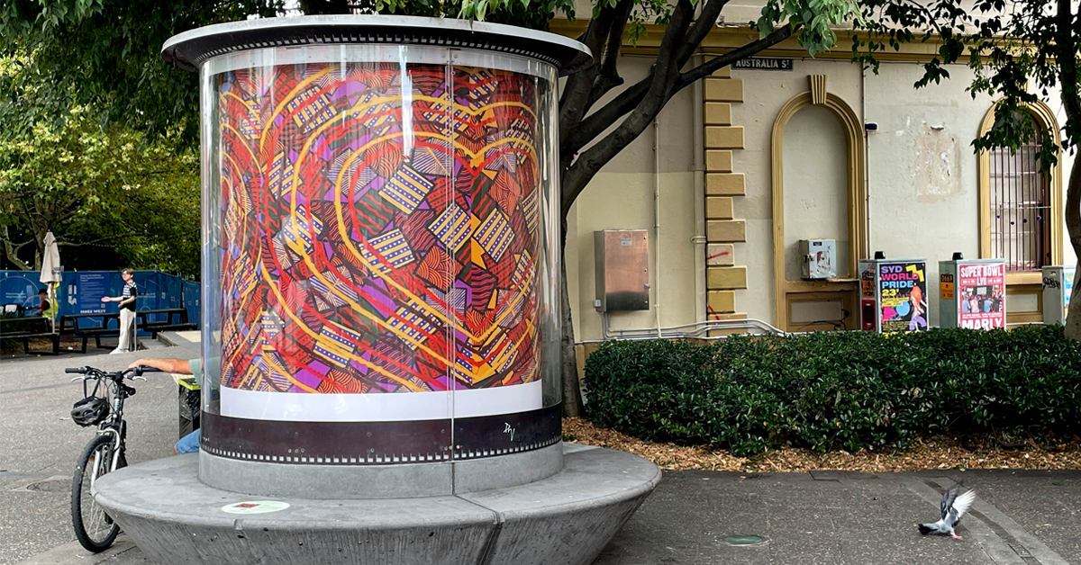 A colourful artwork sits inside a round glass housing on a street