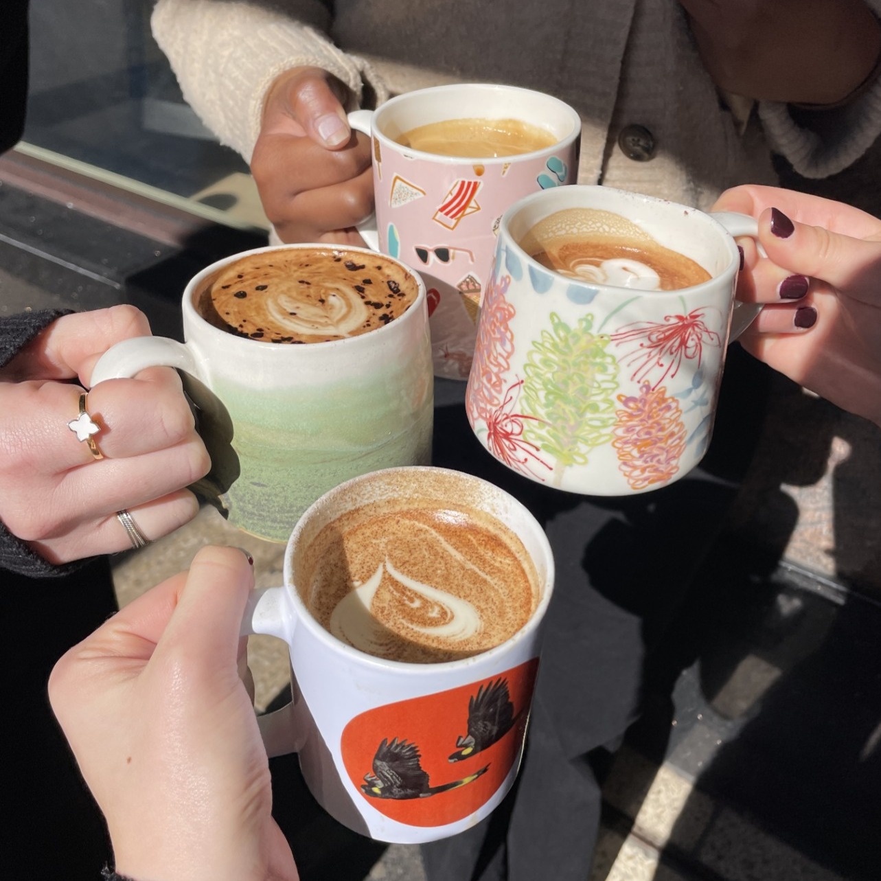 hands holding mugs of coffee