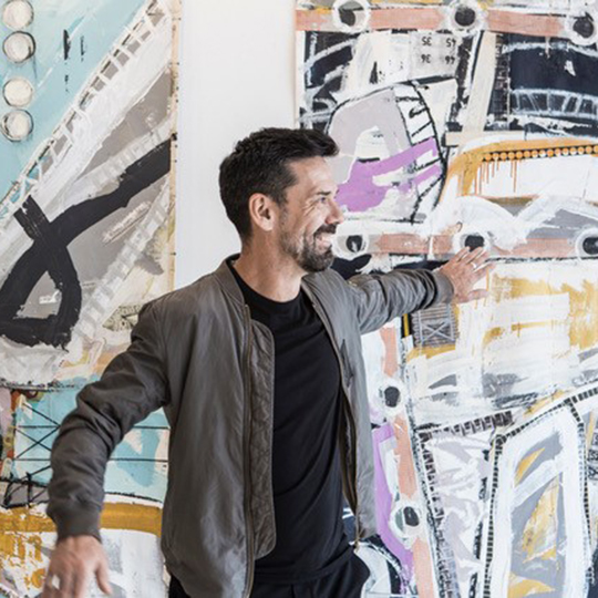 Artist in his studio in front of an abstract painting 