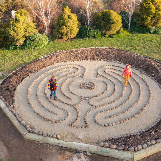 two people dressed colourfully walking around a flat maze made of stones