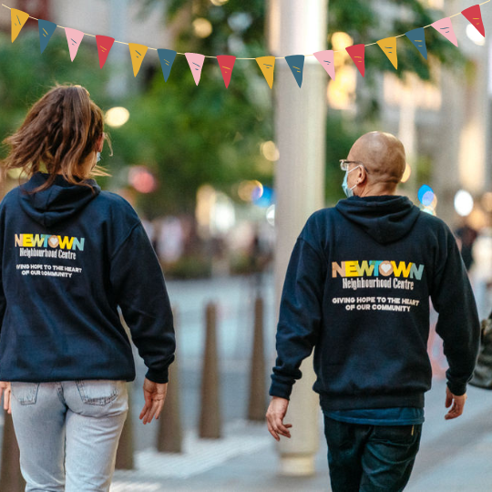 Back images of two people walking wearing NNC sweaters