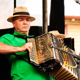 A man in a green shirt plays an accordian