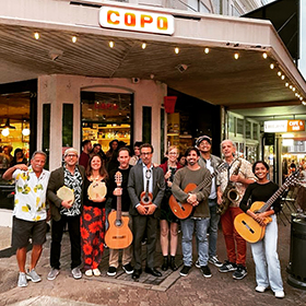 A group of musicians with guitars in front of a restaurant