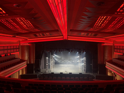 The interior of a historic concert venue bathed in atmospheric red light.