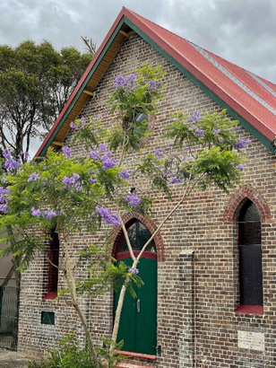 A pointed church-like brick building with a tin roof and arched windows.