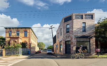 A street intersection with a historic rendered building on the left and a renovated house on the right.