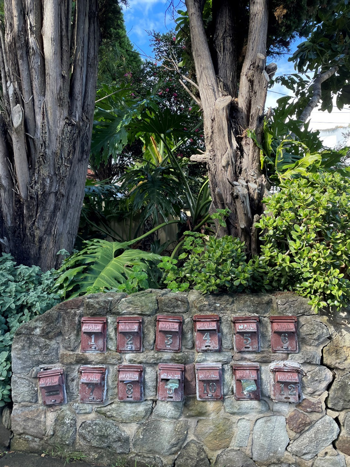 Two rows of old steel mailboxes embedded in a rustic and quaint way into a stone brick wall.