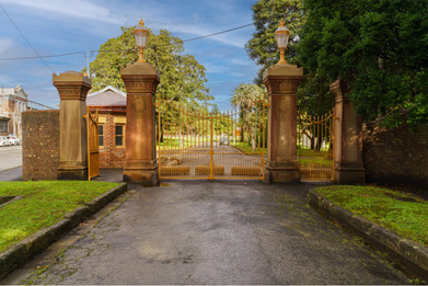 A path leading to a set of historic brick and cast-iron gates.