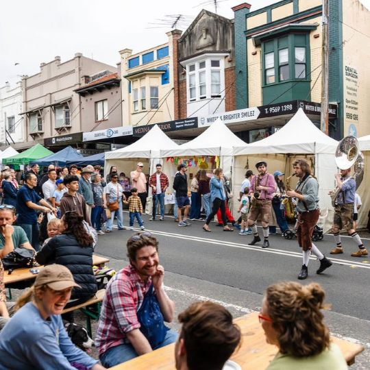 Oompah loompa marching band performing at street fair. people laughing in foreground.