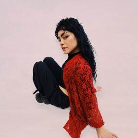 Photo of Miya Zawa sitting on the floor in a red shirt 