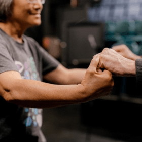 Close up of two people dancing with their hands clenched together