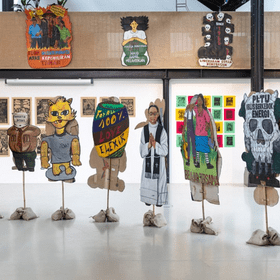 Colourful artworks and pieces of cultural dress in a gallery