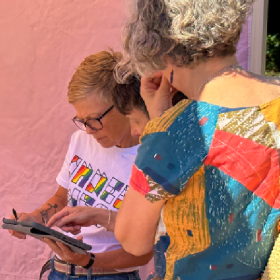 Two people talking; one is pointing to an ipad