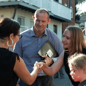 Darcy Byrne smiling as two women shake hands