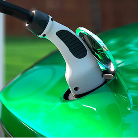EV charger plugged into a modern shiny green car