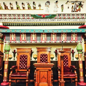 Detail of interior in Egyptian styled room which rectangular wood and red tall red chairs