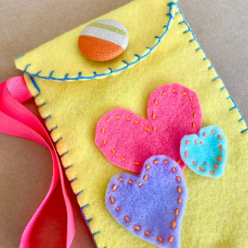 Yellow felt bag with yellow and blue hearts sewn o