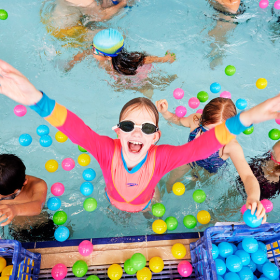 Smiling girl in a pool surrounded by colour flotation devices
