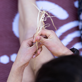 Close up of hands holding string against purple and white patterned fabric