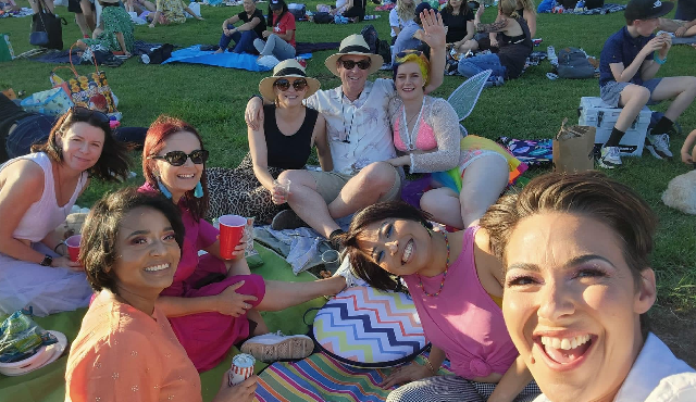 Crowd of smiling people outdoors on picnic blankets