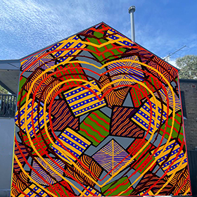 A vibrant coloured Aborigal mural consisting of lines, dots and large hearts on the side of a house