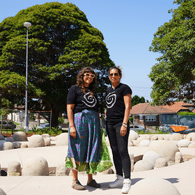 Two people in front of border sculpture in a park