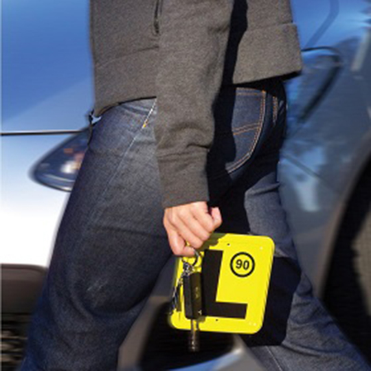 A female holding keys and a yellow learner plate