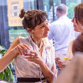 a woman holding a coffee cup is in conversation with another woman