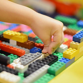 Childs hand placing a brick toy