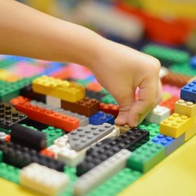Childs hand placing a lego brick