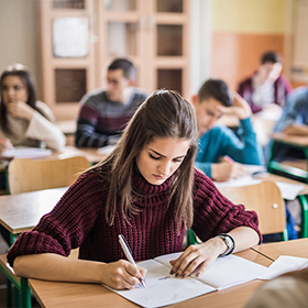 Female high school student writing a test in the classroom