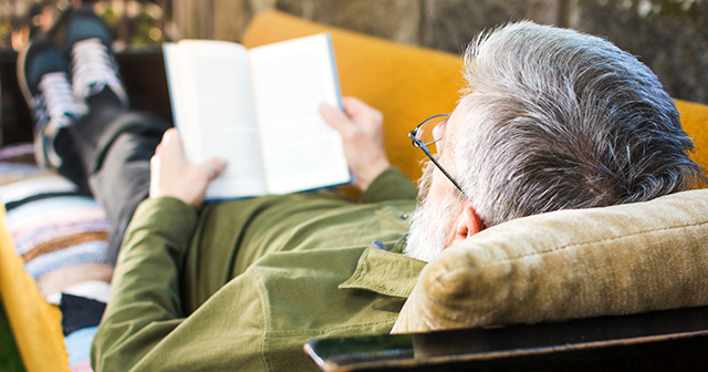 Man on a couch reading a book