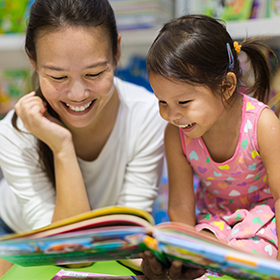 Mother and daughter reading together in a library