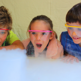 Three children with goggles watch a science show