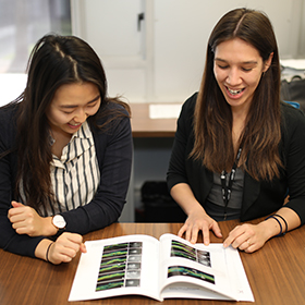 Two women looking at illustrations in a book