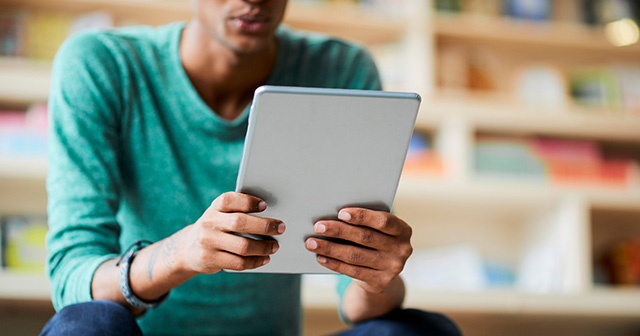 Young man holding a tablet reading an ebook