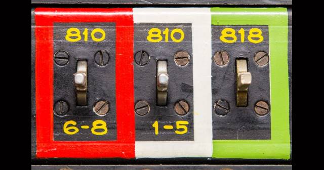 Photo of Balmain Telstra Exchange  switch, photo of three switches in vertical rectangles, first colour bright red, second, white and last pistachio green, switch numbers appear in each rectangle as well as metal switch