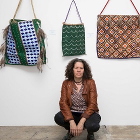 Artist crouching in front of artwork at Boomalli Gallery