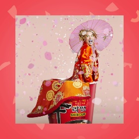 Photo of a person dressed in a large orange kimono with floral pattern, they have a pink umbrella and are sitting on an instant noodle cup, there are pink confetti like shapes overlayed ontop of the image. The person wears blue lipstick and yellow eyeshadow with a golden headpiece decoration