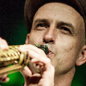 Close up of man in woollen hat playing brass instrument