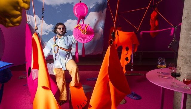 Hossei posed in his art installation, fabrics of pink and orange with a blue sky in the backdrop