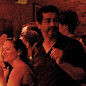 Deep red sepia tone photo of a group of people in what looks like a bar