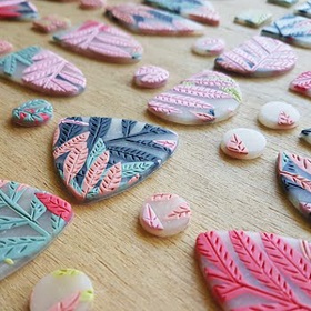 Resin or clay small circles, crescents and round cornered triangles with leaf motifs, pastel colours, pink, coral, dark blue, aqua and pistachio green. Could be jewellery in the making