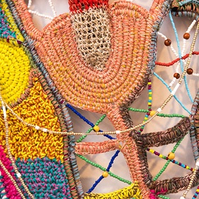 Up close photo of weaving detail on a range of woven pieces, coral orange, blue, yellow, beading