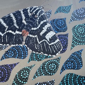 Painting of a black and white moth, underneath the moth is a repeat pattern of what looks like a terdrop shape that has decorative circulr dot print, the teardrop shapes are black with blue, green, purple and aqua colours  for the dots